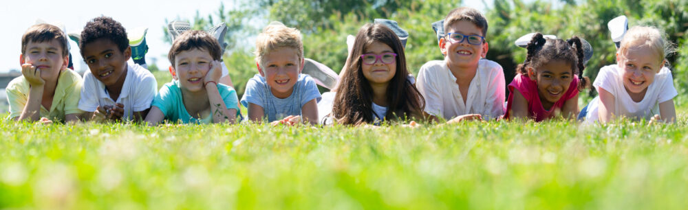 Kinder liegen gemeinsam lachend auf einer Wiese